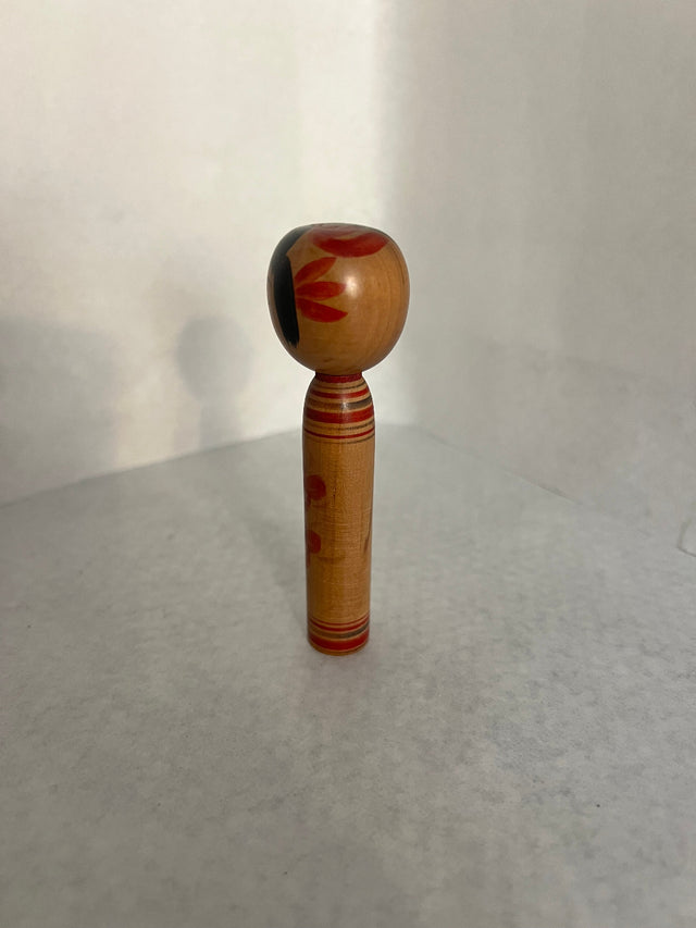 Vintage kokeshi #25 set fra siden. Rød stribet hals og svage blomster. 10 cm
