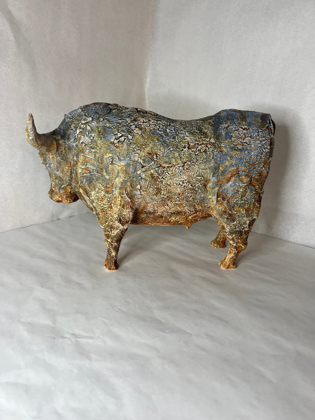 Keramikskulptur af bison set bagfra med massivt skulderparti i blågrå og gyldne toner