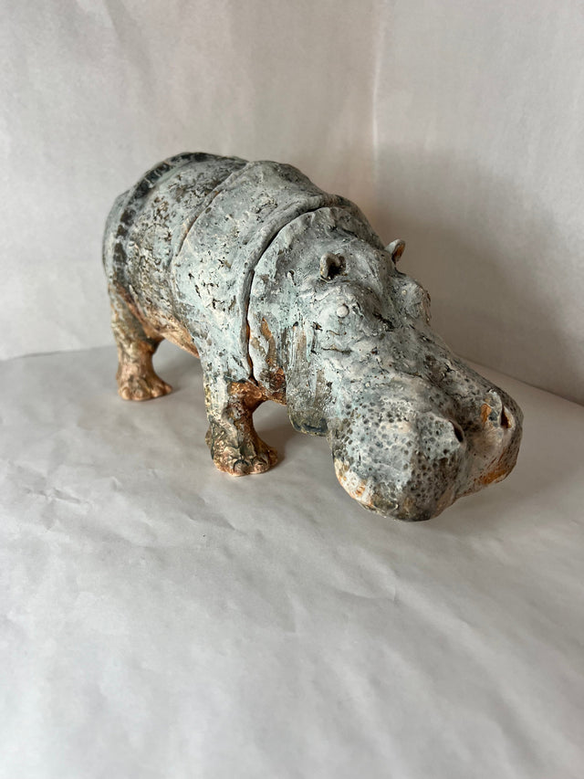 Keramikskulptur af flodhest set skråt forfra med det sænkede hoved og grå-grøn glasur