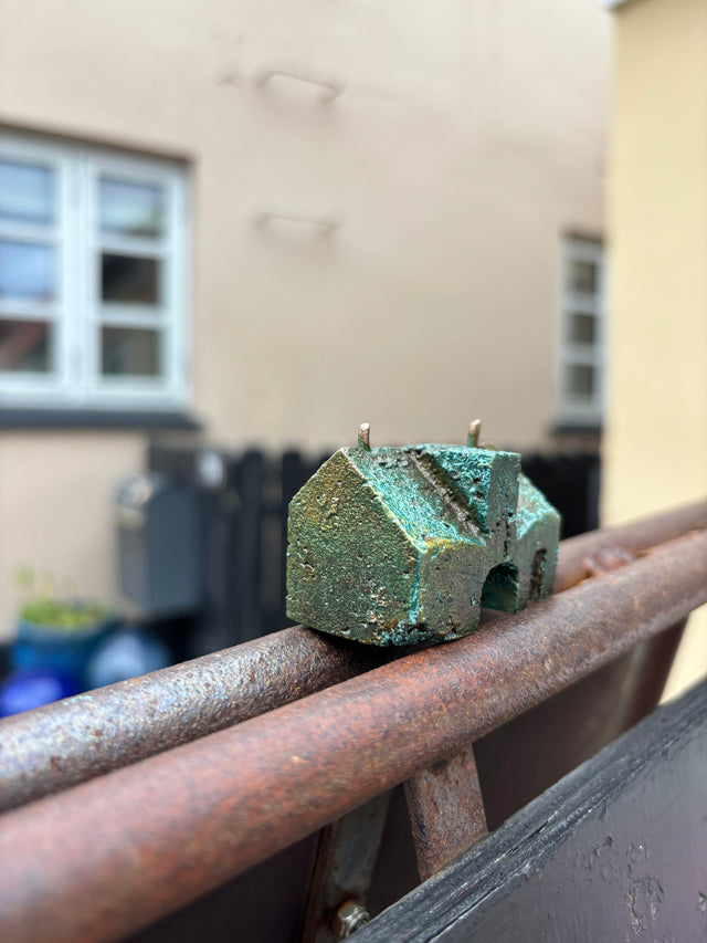Hus #12 fra Harritsø på en rusten gelænder - lille bronze skulptur med blågrøn patina