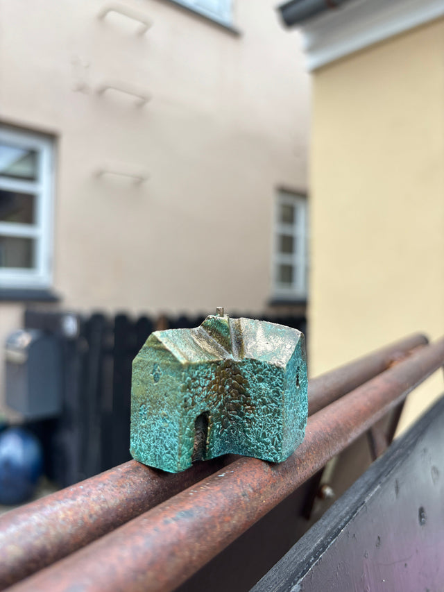Hus #16 fra Harritsø på en rusten gelænder - blågrøn bronze skulptur med komplekst tag