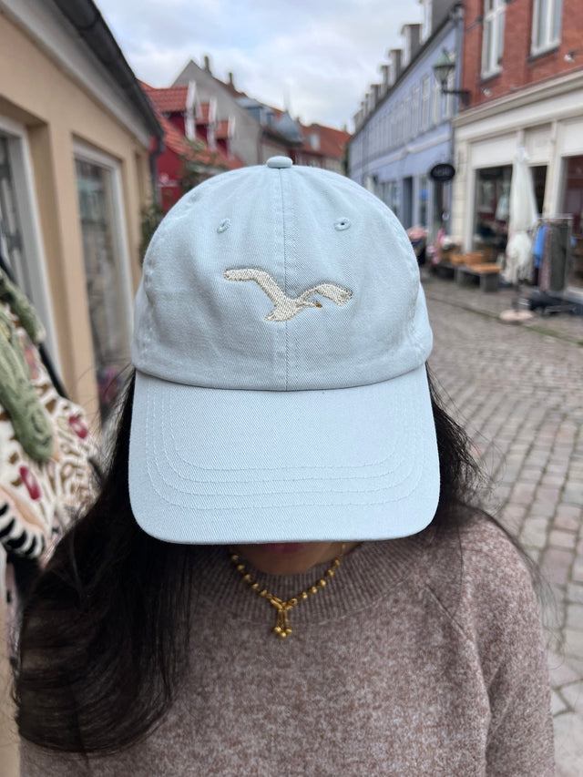 Kasket med broderet flyvende svane i lys blå fra Rustfelt, fotograferet i Ebeltofts gågade