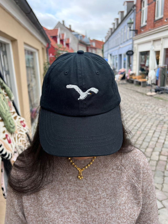 Kasket med broderet flyvende svane i sort fra Rustfelt, fotograferet i Ebeltofts gågade