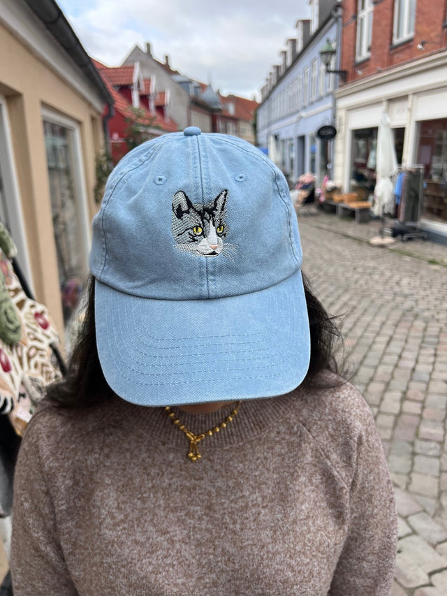 Kasket med broderet grå kat i blå fra Rustfelt, fotograferet i Ebeltofts gågade