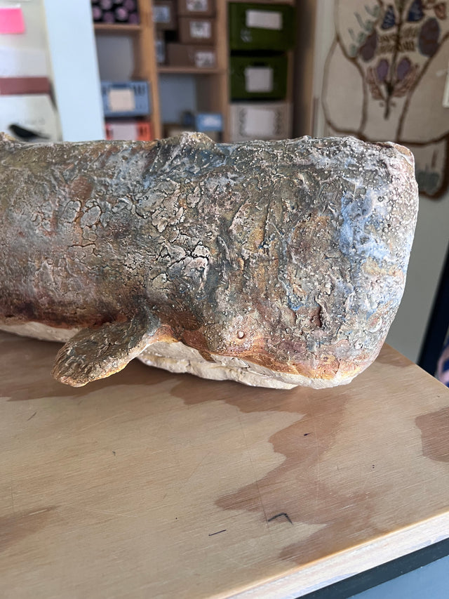 Keramik kaskelothval 06 set fra siden paa traebord - graabrunt glasur med blaagraa og orange undertoner