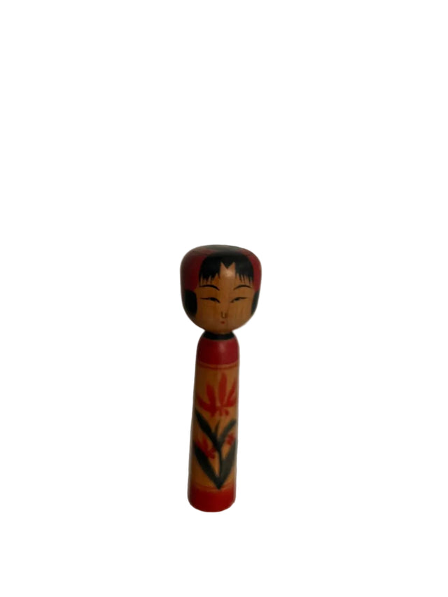 Vintage kokeshi dukke med rød hat, sort hår og rød-sort blomst-bladmotiv. 10 cm