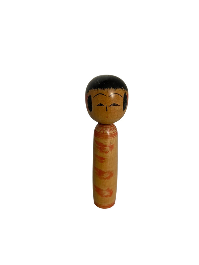 Vintage kokeshi dukke med sort flad hat og svage orange bladmotiver på lyst træ. 10 cm