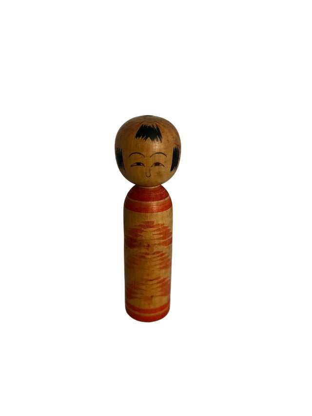 Vintage kokeshi dukke i lyst træ med orange penselstrøg som varm tekstur. Enkel. 10 cm