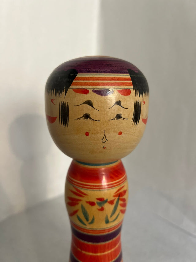 Nærbillede af håndmalet ansigt på vintage kokeshi #18. Lilla hat og røde prikker. 25 cm