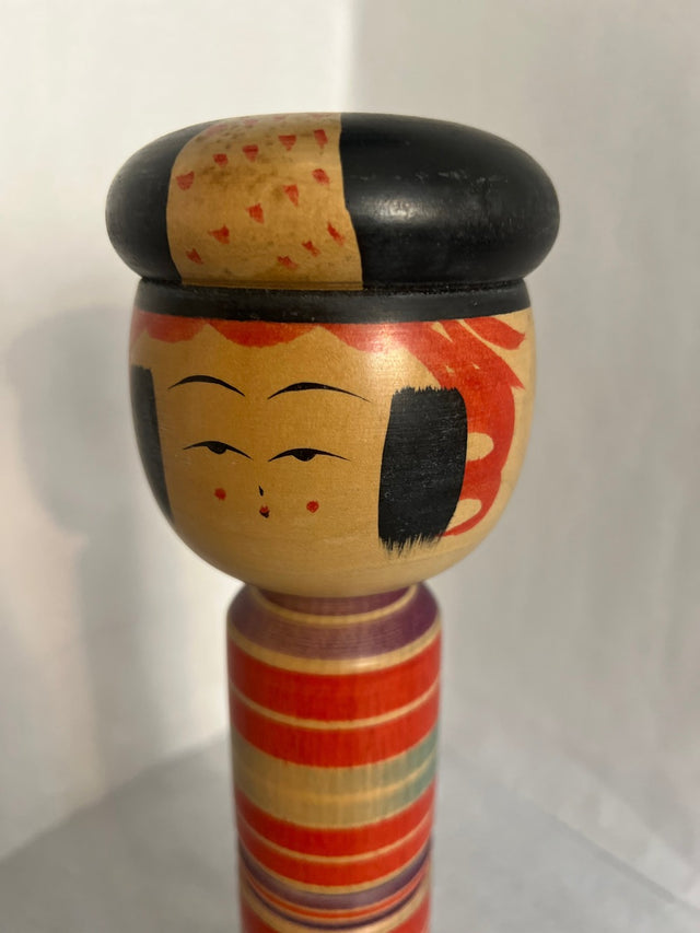 Nærbillede af håndmalet ansigt på vintage kokeshi #11. Røde pletter og sort hat. 31 cm