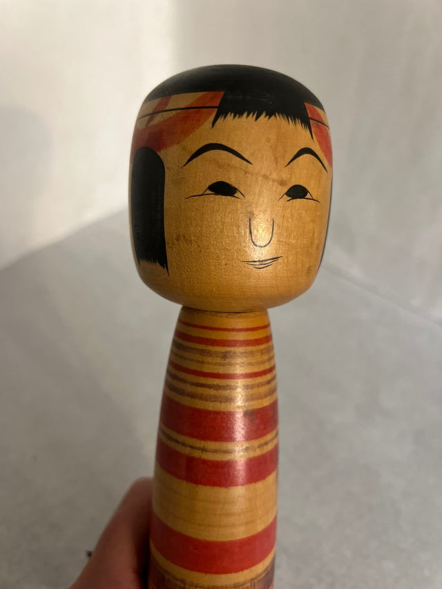 Nærbillede af håndmalet ansigt på vintage kokeshi #14. Sort hår og smilende mine. 26 cm