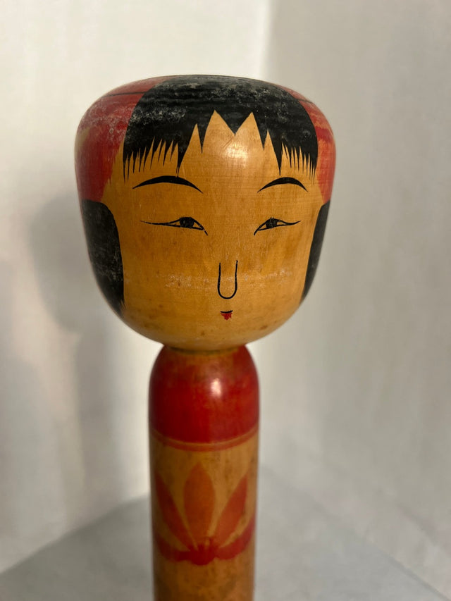 Nærbillede af håndmalet ansigt på vintage kokeshi #10. Rødt hoved og store øjne. 31 cm