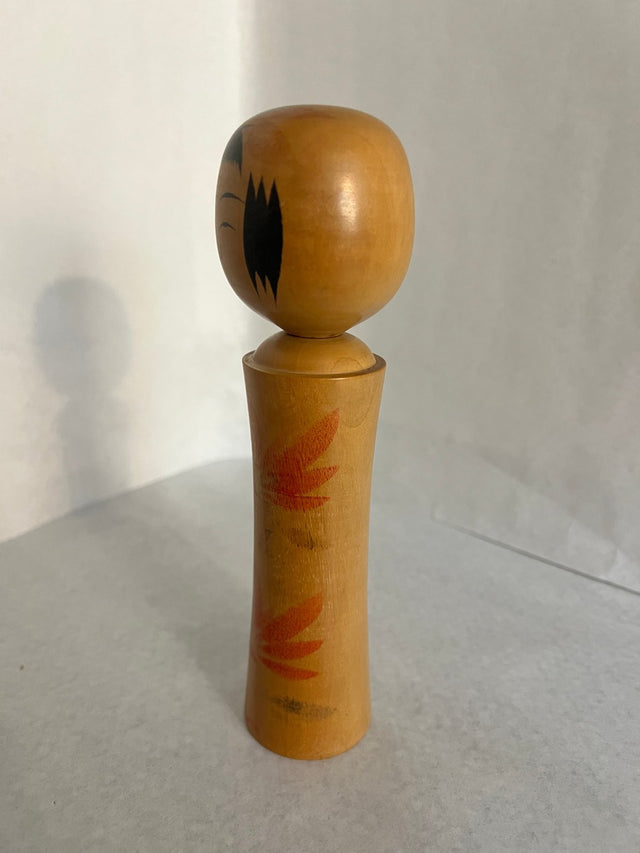 Vintage kokeshi #21 set fra siden. Røde lotus/flammemotiver. 19 cm