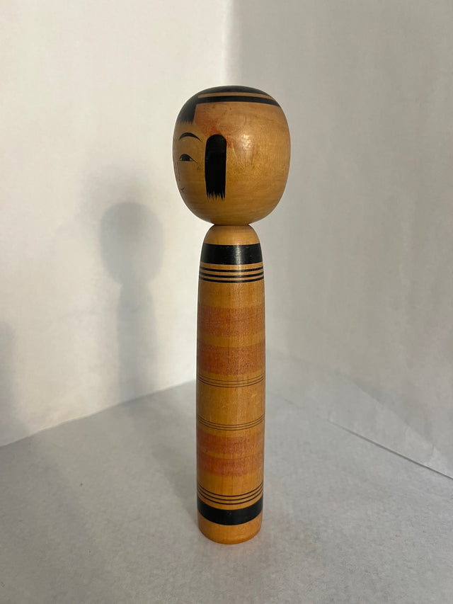 Vintage kokeshi #17 set fra siden. Brede orange og røde striber. 25 cm