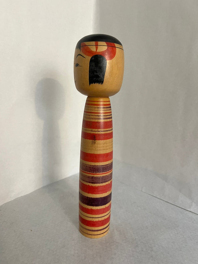 Vintage kokeshi #14 set fra siden. Røde og brune striber. 26 cm