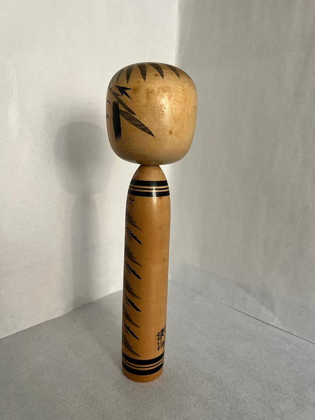Vintage kokeshi #07 i skrå vinkel. Sort granmønster ned ad krop. 33 cm