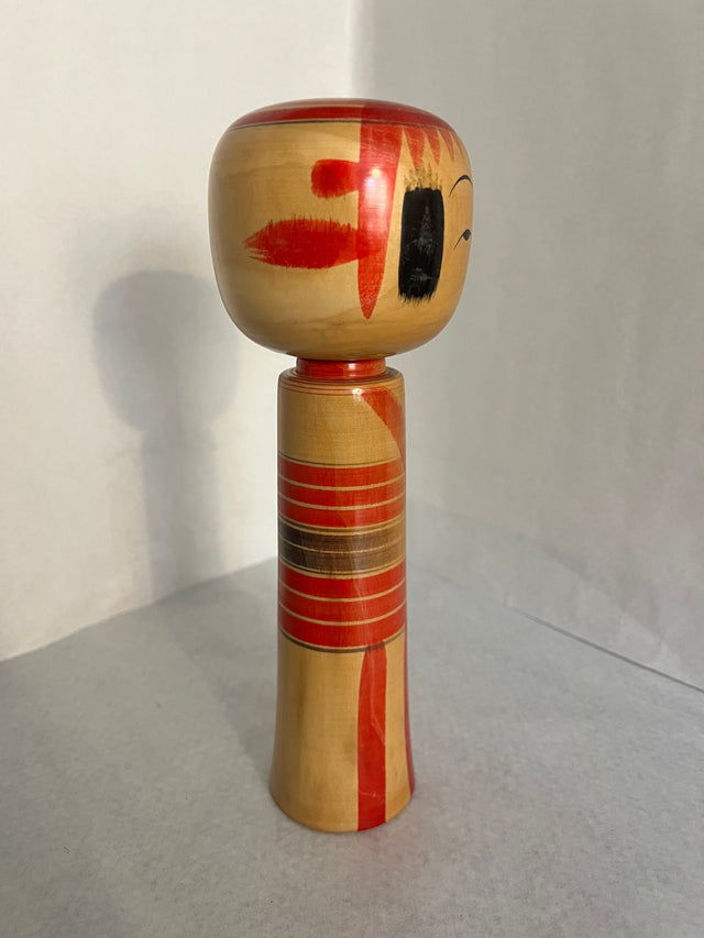 Vintage kokeshi #19 i skrå vinkel. Røde og orange geometriske motiver. 25 cm