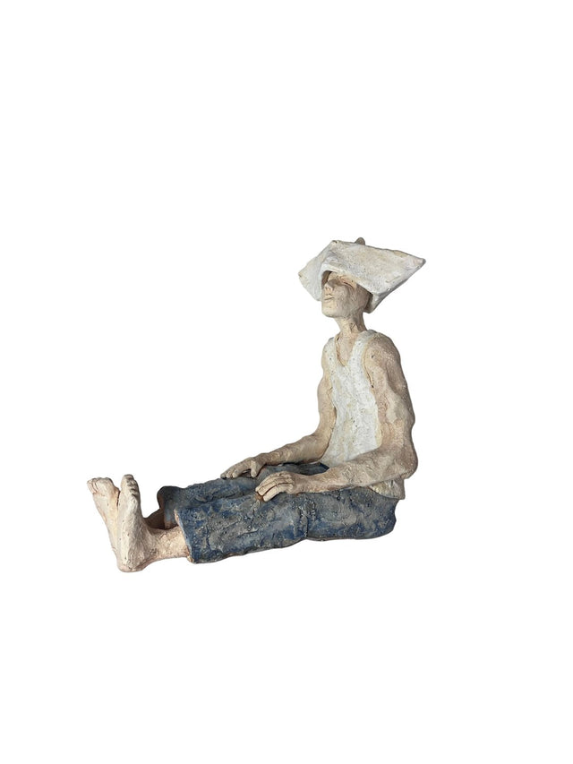 Keramikskulptur Mand med avishat 01 i creme og blå, siddende med ben strakt - Ponyklubben