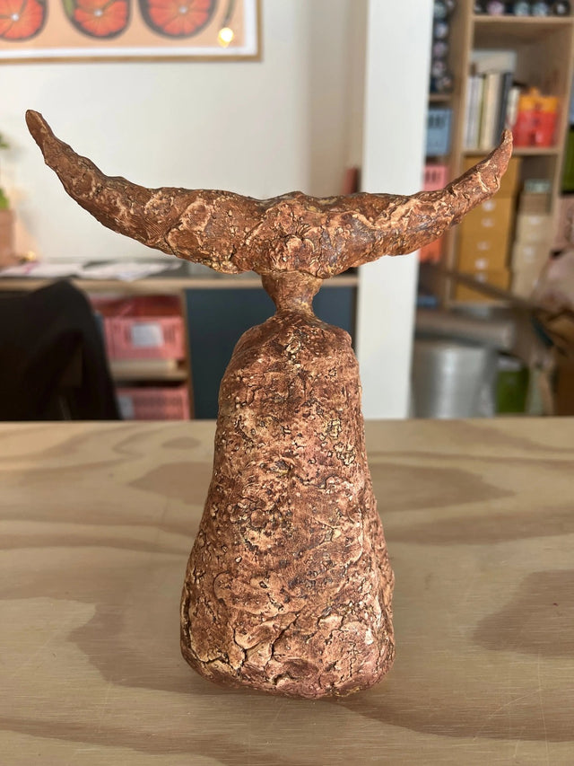 Keramikskulptur med brede horn i terrakotta set bagfra med kompakt rund krop